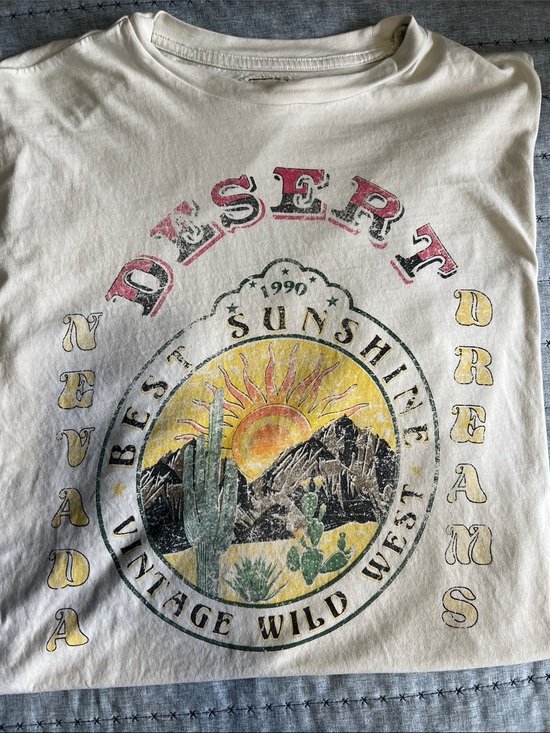 Modish Rebel Tops - Cream colored Buckle short sleeved shirt features a vintage graphic